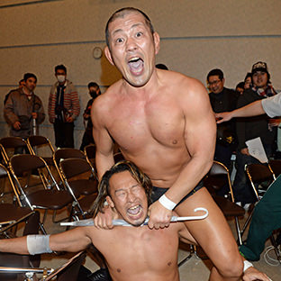 鈴木みのる×丸藤正道、丸藤正道に場外で傘を使って首を絞める鈴木みのる（上）