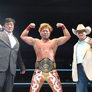 3冠ヘビー級のベルトを奪取した宮原健斗（中）とプレゼンターを務めた小橋建太（左）とスタン・ハンセン（右）