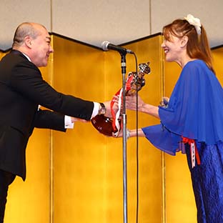 西村誠司社長(左)からトロフィーを贈呈されるブル中野